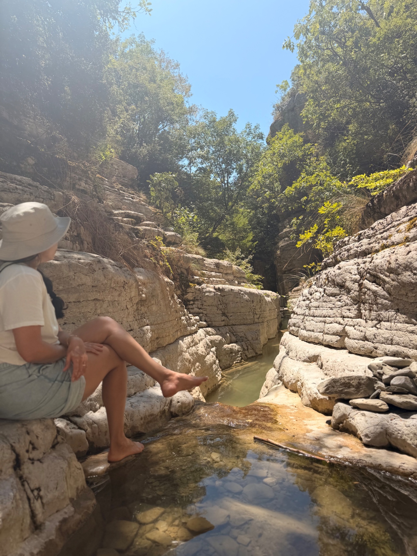 אמא יושבת על סלע ומשכשכת רגליים בבריכות רוגובוס